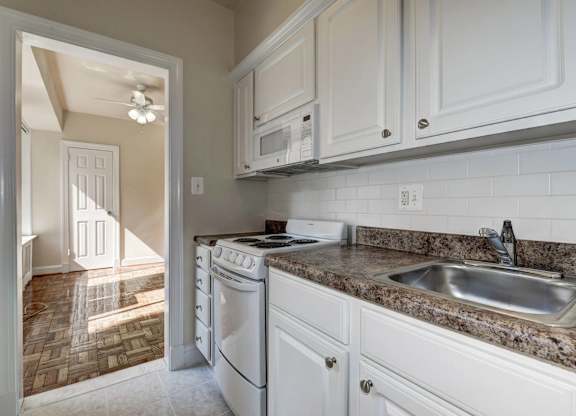 A kitchen with a white dishwasher and a granite countertop.