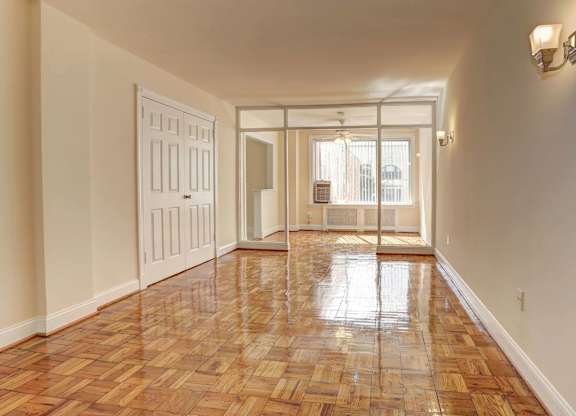 A long hallway with a wooden floor and a white door.