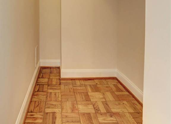 A hallway with a wooden floor and white walls.
