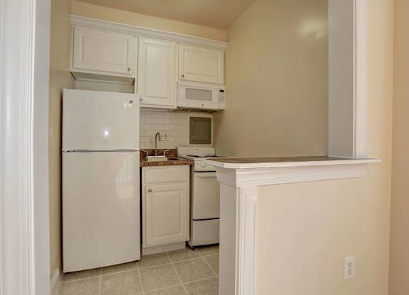 A kitchen with white appliances and cabinets.