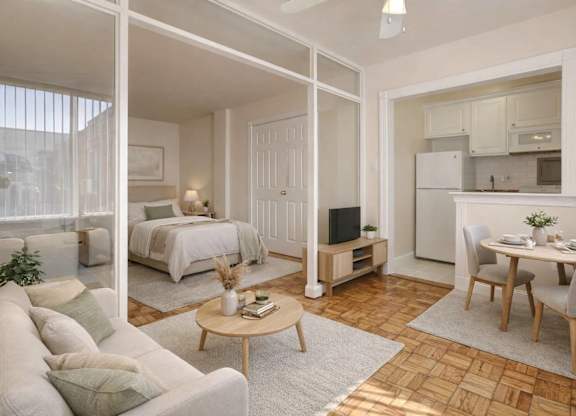 A well-lit, spacious living room with a couch, coffee table, and a bedroom area in the background.