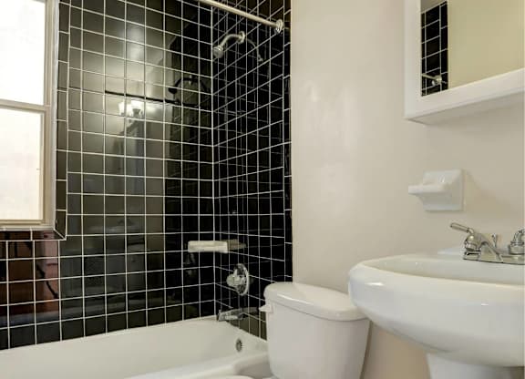 A white toilet sits in a bathroom with black tiles.