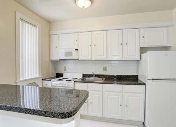 Kitchen with white cabinets and granite countertops at Tivoli Gardens Apartments