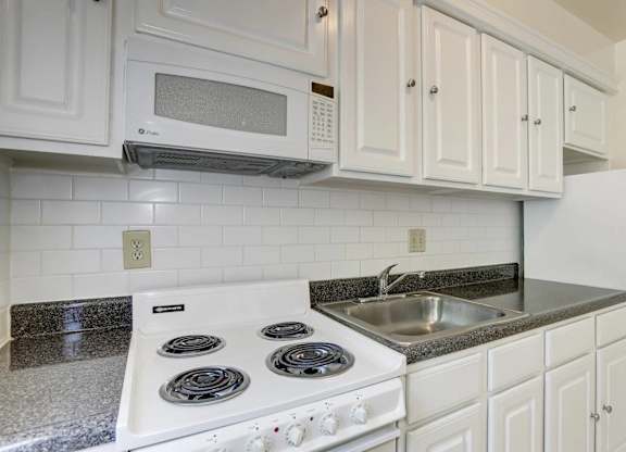 Kitchen with white appliances and subway tile backsplash at Tivoli Gardens Apartments, 20010