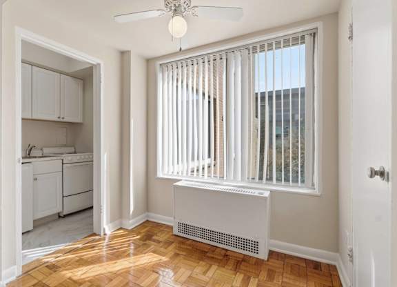 A room with a window covered by white blinds and a white radiator on the wall.