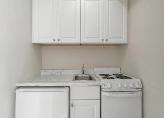A white kitchen with a dishwasher, sink, and stove.