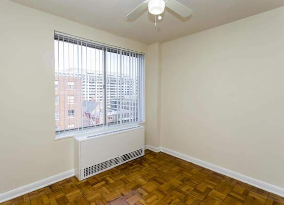 A room with a window and a fan on the ceiling.