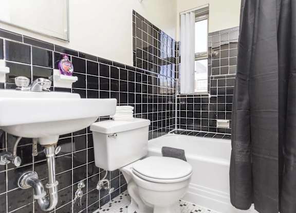 A white toilet and sink in a black and white tiled bathroom.