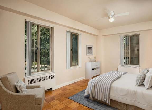 A bedroom with a bed, chair, and window.