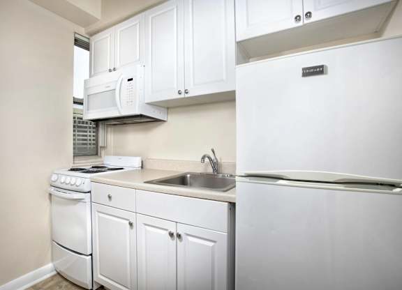 A white kitchen with a refrigerator, stove, and microwave.