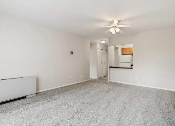 A spacious room with a carpeted floor and a ceiling fan.
