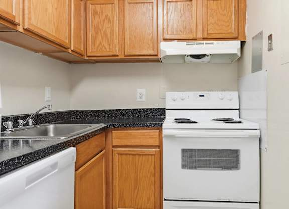 A kitchen with a white stove and white dishwasher.