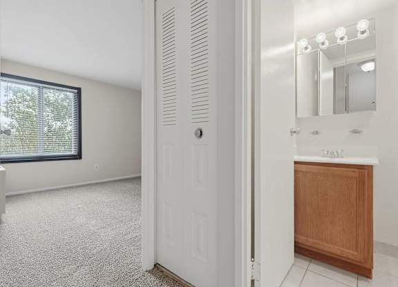 A white door is open to a bathroom with a sink and mirror.