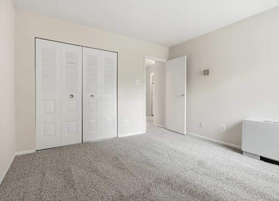 A room with white walls and a grey carpet.