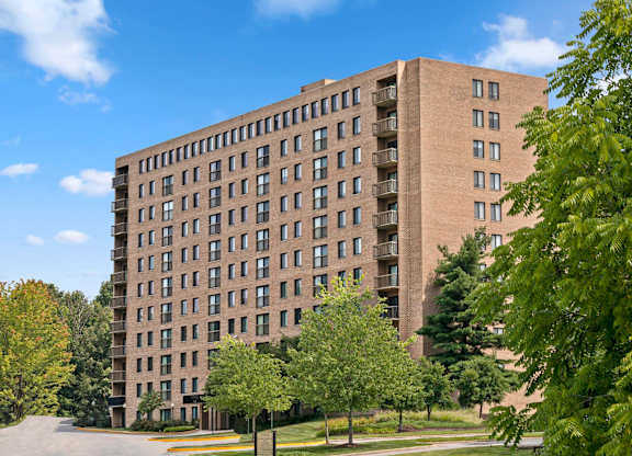 A tall building with many windows is surrounded by trees.