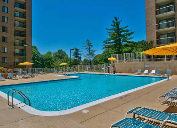 A large swimming pool surrounded by lounge chairs and umbrellas.