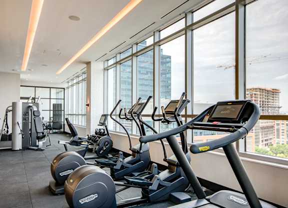 Fitness center with cardio equipment and city views at 1405 Point Apartments, Baltimore, MD 21231