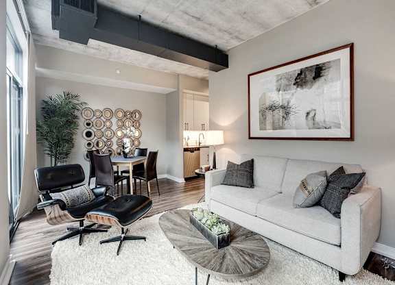 A living room with a grey couch, a black chair, and a wooden coffee table.