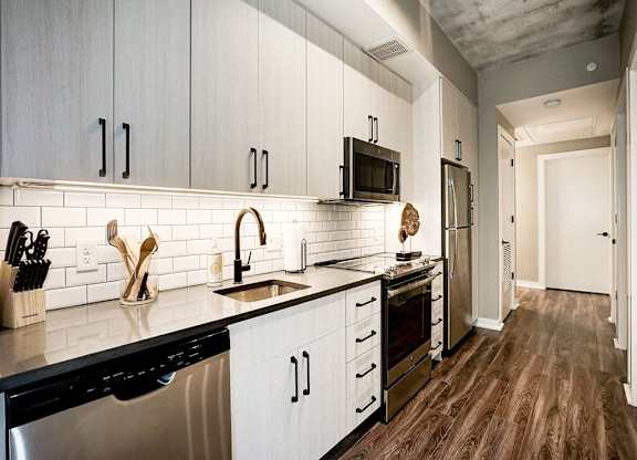 A kitchen with white cabinets and black appliances.
