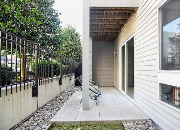 A small patio with a table and chairs is surrounded by a metal fence.