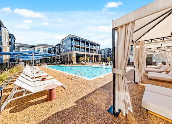 A pool area with sun loungers and a cabanas at Preston Ridge Apartments in Cary, NC.