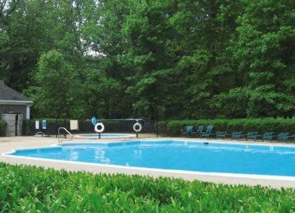 A pool surrounded by greenery and trees at Shenandoah Station Apartments, Triangle, Virginia
