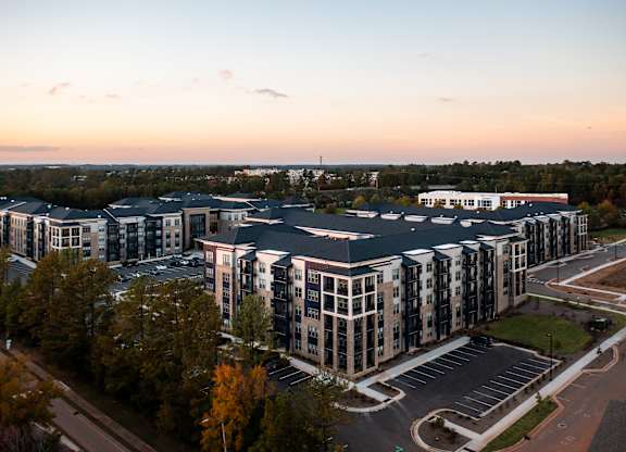 A large, modern building complex with a parking lot in front.