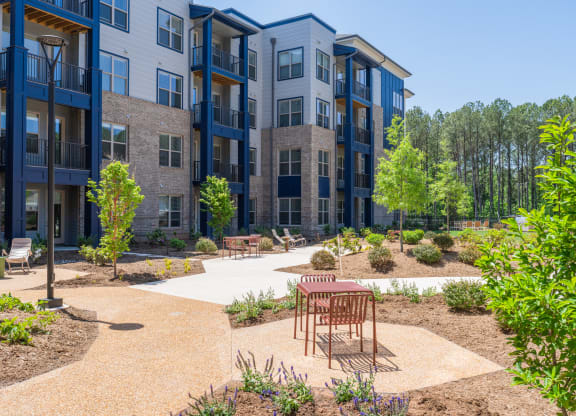 an outdoor area with a table and chairs in front of an apartment building at Preston Ridge, North Carolina