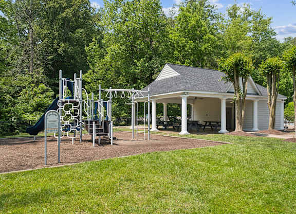 A playground with a swing set and a gazebo in the background.