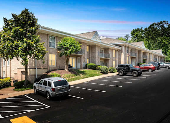 A parking lot in front of a building with cars parked.