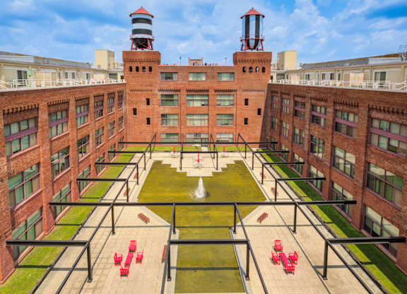 A courtyard with a fountain and red chairs surrounded by brick buildings.