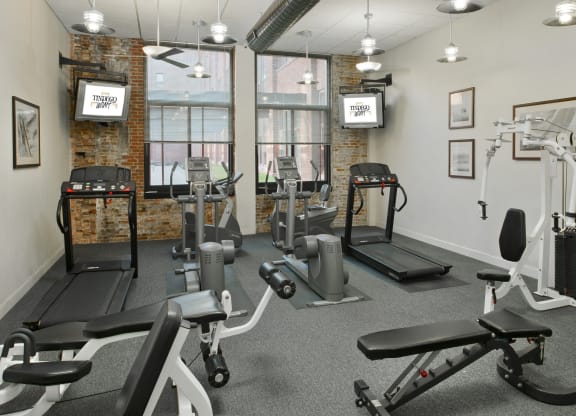 a gym with weights and exercise equipment in a room with windows at Tindeco Wharf, Baltimore, MD