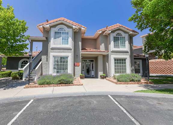 A two-story house with a red tile roof and a driveway in front at West Park Apartments, Albuquerque