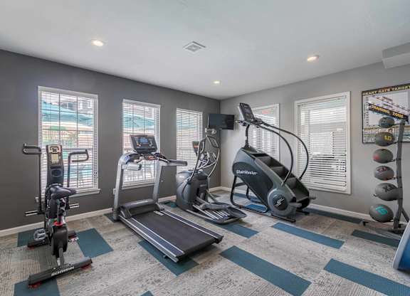 A spartan room with a treadmill, exercise bike, and other equipment at West Park Apartments, Albuquerque
