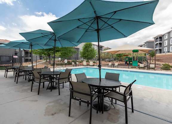 A patio with a table and chairs under umbrellas at West Park Apartments, Albuquerque