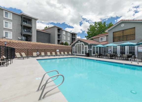 A large swimming pool with a diving board and lounge chairs at West Park Apartments, Albuquerque