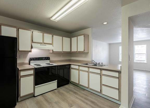 A kitchen with black appliances and white cabinets at West Park Apartments, Albuquerque