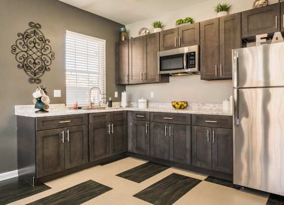 A kitchen with brown cabinets and a white fridge at West Park Apartments, Albuquerque, NM, 87114