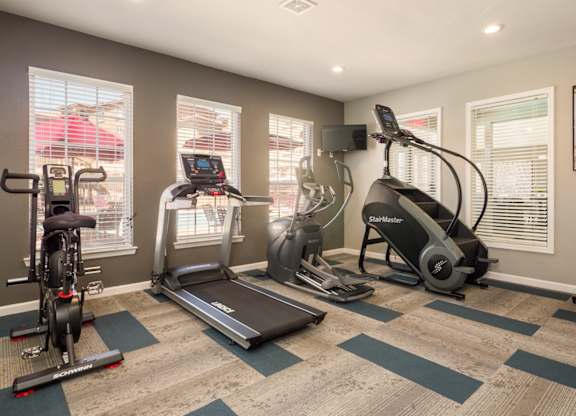 A home gym with a treadmill, elliptical trainer, and stationary bike at West Park Apartments, Albuquerque, New Mexico