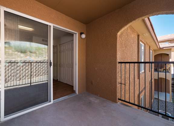 A balcony with a view of a fence and a building at West Park Apartments, Albuquerque, 87114