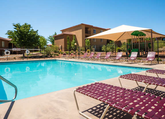 A pool with a white umbrella and red chairs at West Park Apartments, Albuquerque, NM, 87114