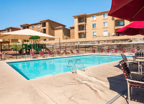 A pool with a red umbrella and a slide at West Park Apartments, New Mexico 87114