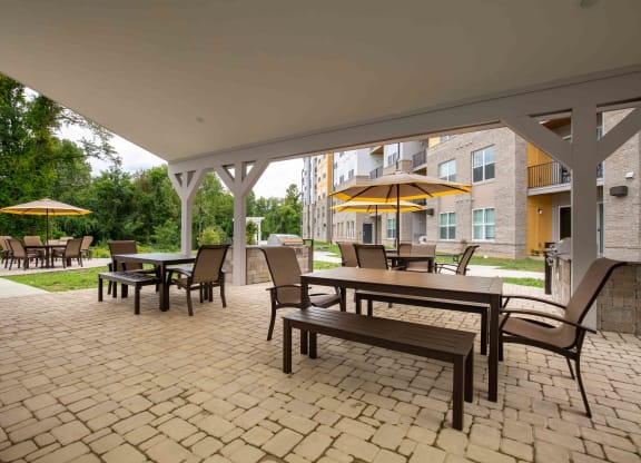 a covered patio with tables and chairs and umbrellas at Woodmore Grand, Bowie