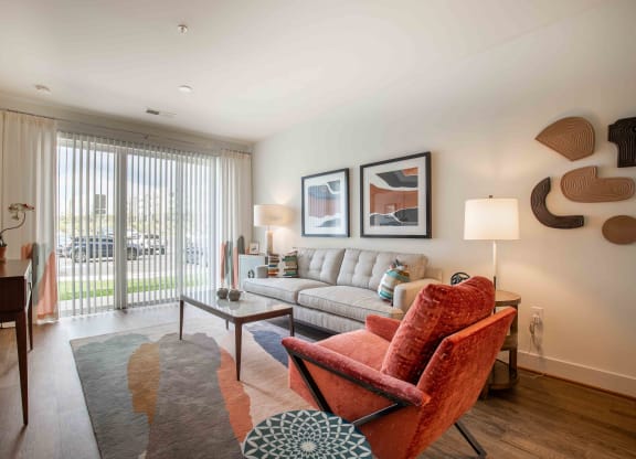 a living room with a couch and a chair and a window at Woodmore Grand, Bowie