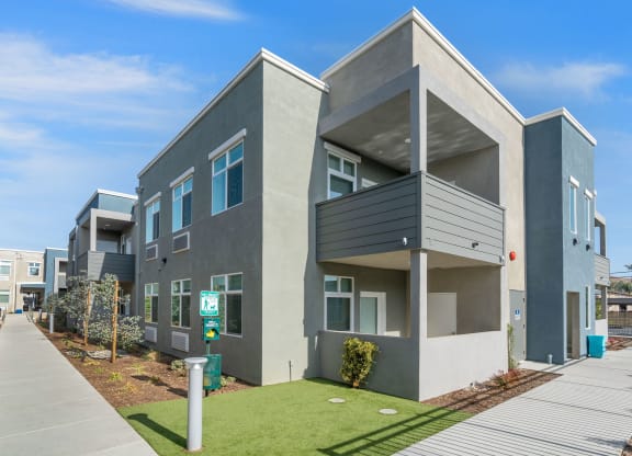 a picture of a building with a green lawn and blue sky in the background at Loma Villas Apartments, San Bernardino California