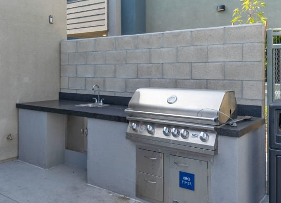 an outdoor kitchen with a grill and sink at Loma Villas Apartments, California, 92408