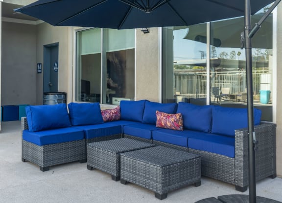 a patio with a blue sectional sofa and gray wicker chairs at Loma Villas Apartments, California