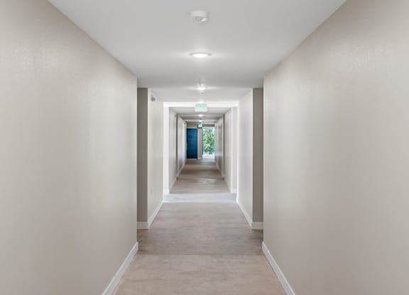 a long corridor with white walls and beige carpet at Loma Villas Apartments, San Bernardino California