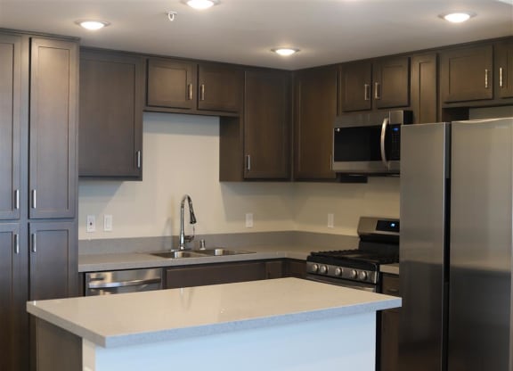 a kitchen with a white counter top and a stainless steel refrigerator at Loma Villas Apartments in San Bernardino, CA