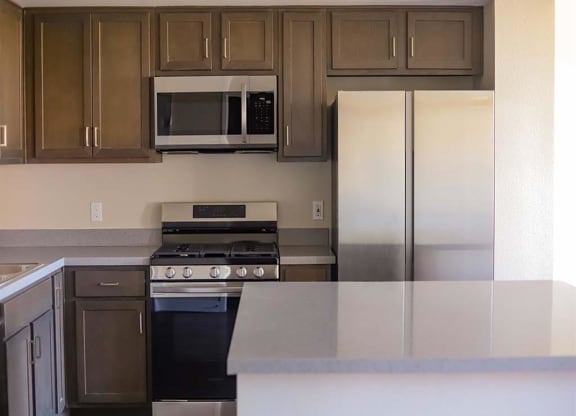 a kitchen with a stove microwave and refrigerator at Loma Villas Apartments in San Bernardino, CA